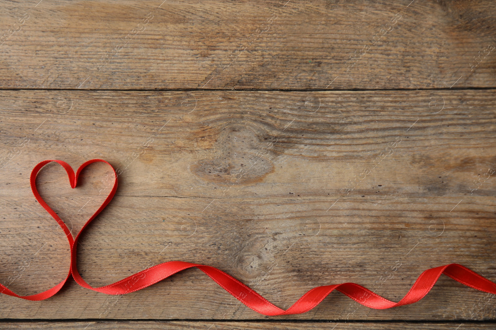 Photo of Heart made of red ribbon on wooden background, top view with space for text. Valentine's day celebration