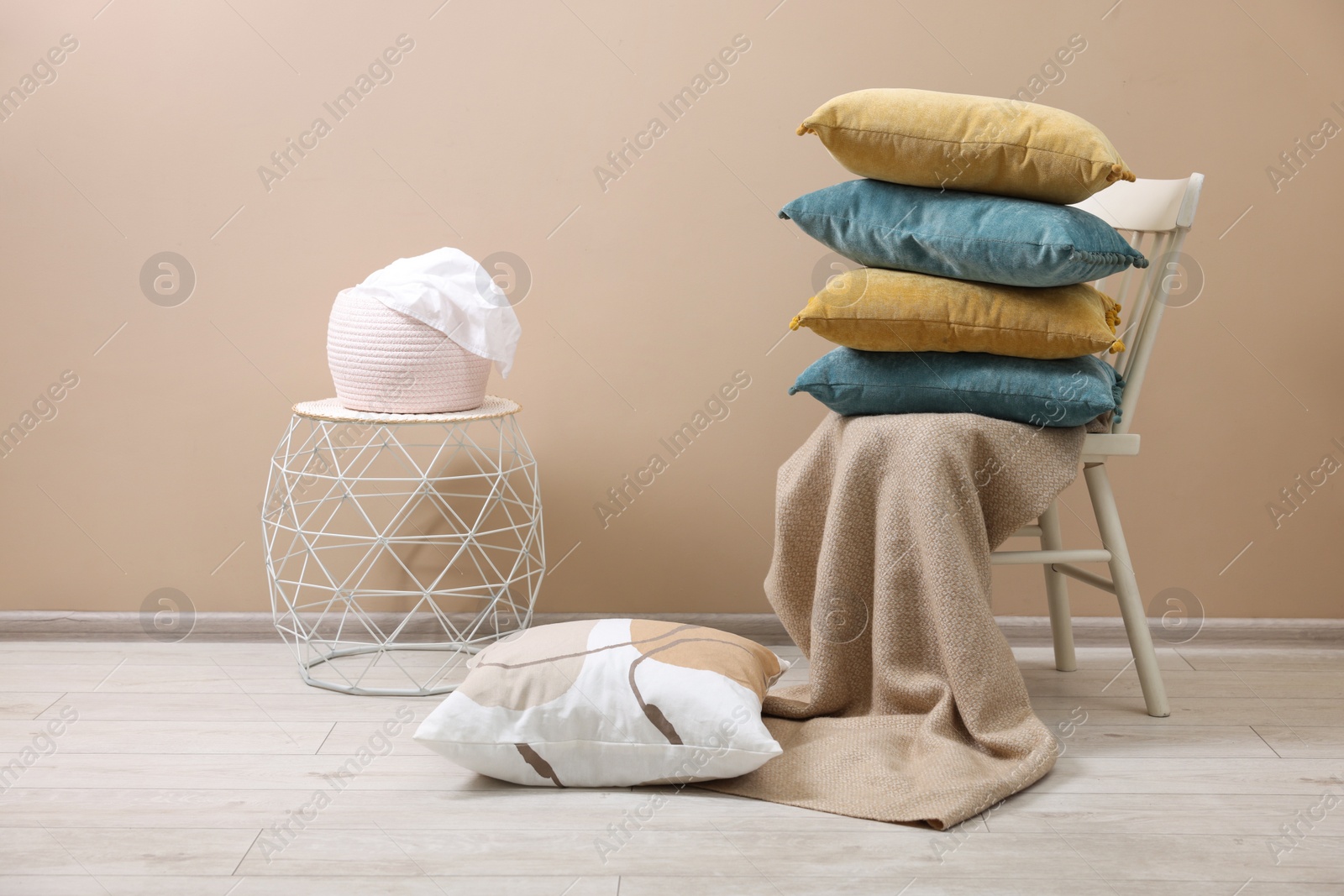 Photo of Soft pillows and warm blanket near beige wall indoors