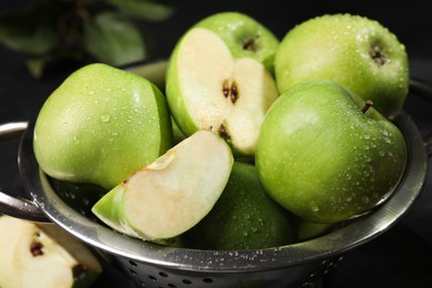 Photo of Ripe green apples with water drops in colander on table, closeup
