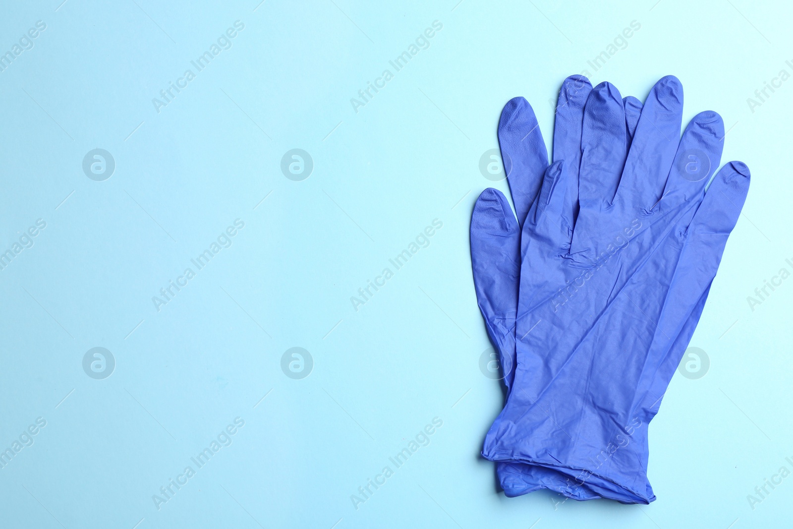 Photo of Pair of medical gloves on light blue background, flat lay. Space for text