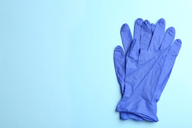 Pair of medical gloves on light blue background, flat lay. Space for text