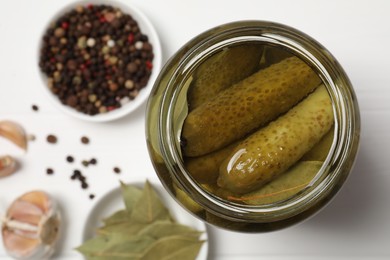 Tasty pickled cucumbers in jar and ingredients on white table, top view