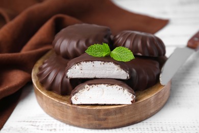 Photo of Delicious chocolate covered marshmallows with mint on white wooden table