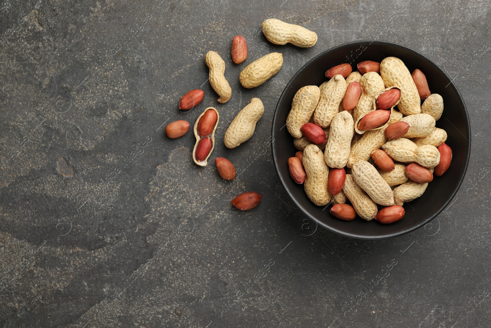 Photo of Fresh unpeeled peanuts in bowl on grey table, top view. Space for text