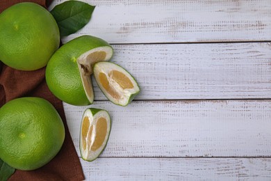 Photo of Whole and cut sweetie fruits on white wooden table, flat lay. Space for text