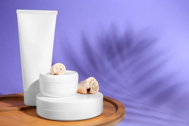 Jars, tube of cream and seashells on violet background, space for text