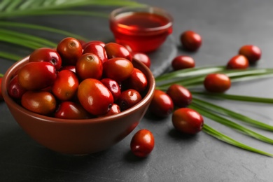 Palm oil fruits in bowl on black table, closeup