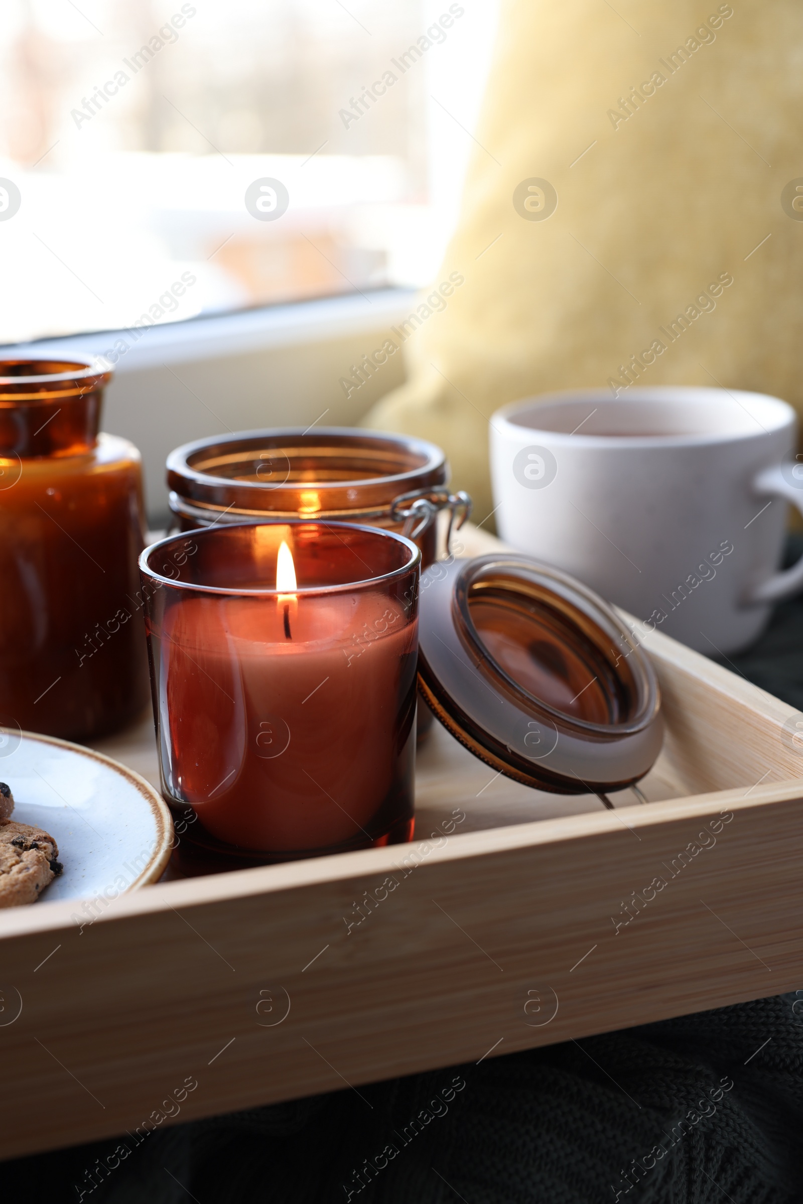 Photo of Tray with burning candles near window indoors