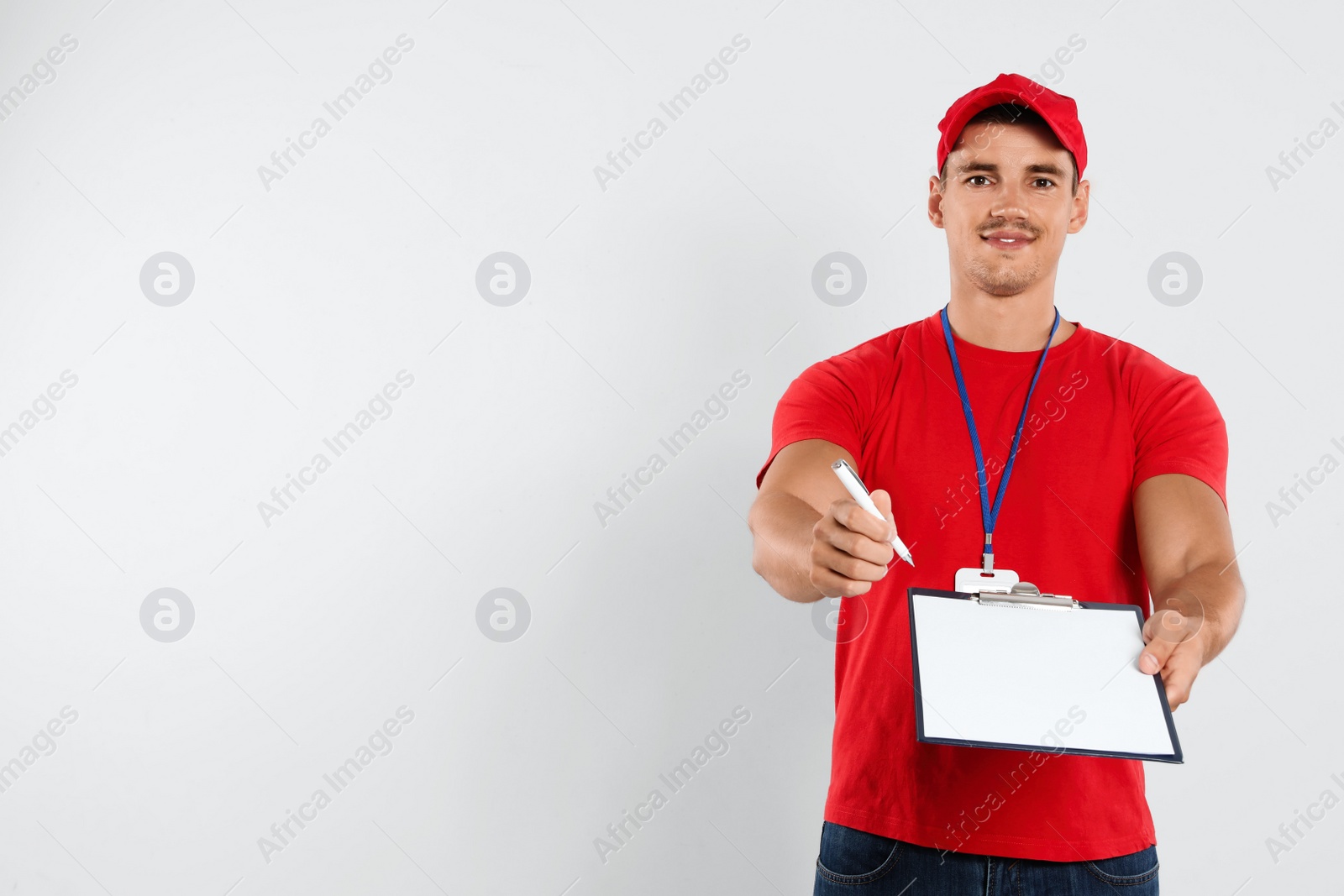 Photo of Happy young courier with clipboard on white background. Space for text