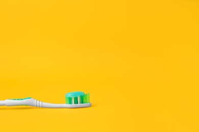 Photo of Brush and toothpaste on yellow background, space for text