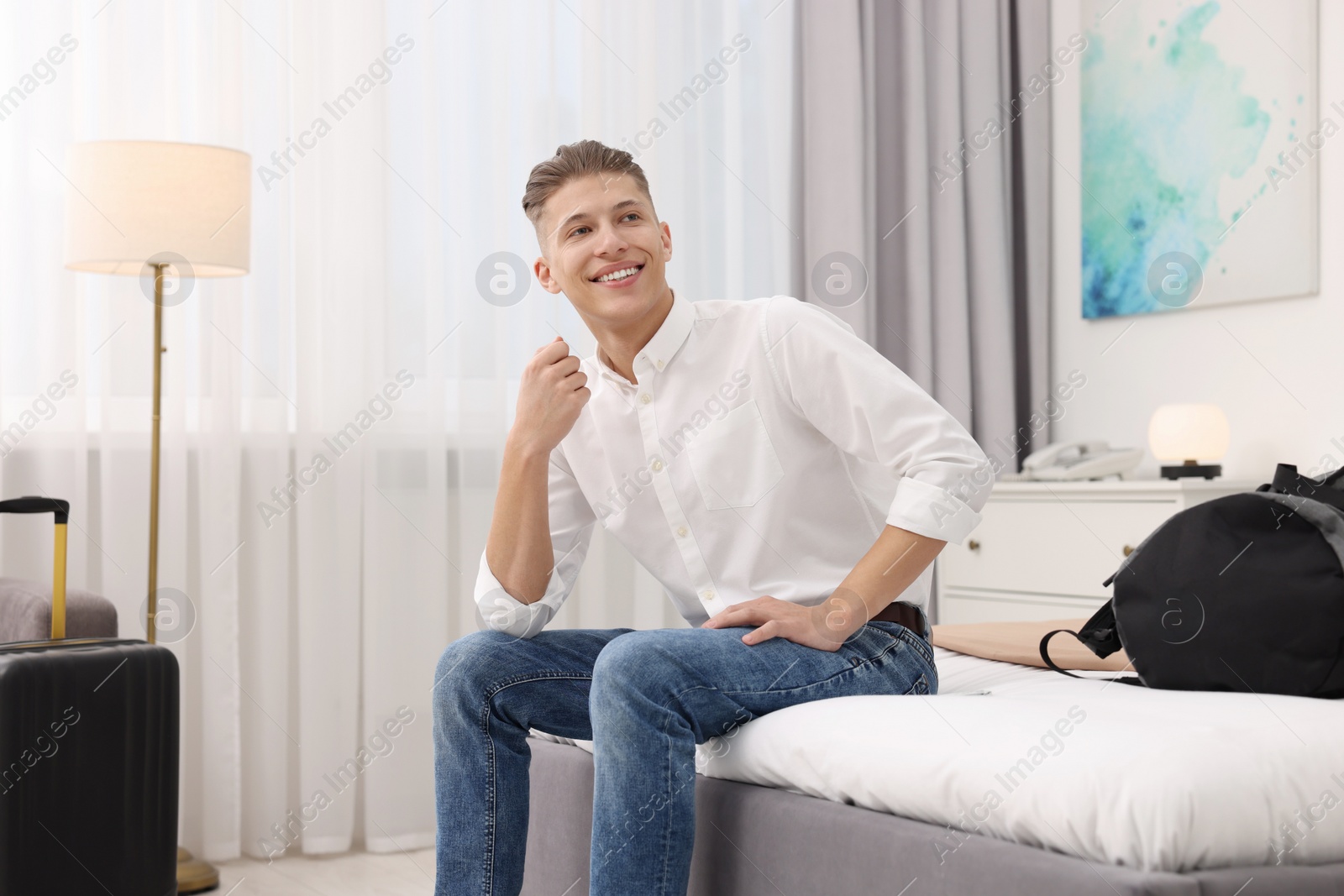 Photo of Smiling guest relaxing on bed in stylish hotel room