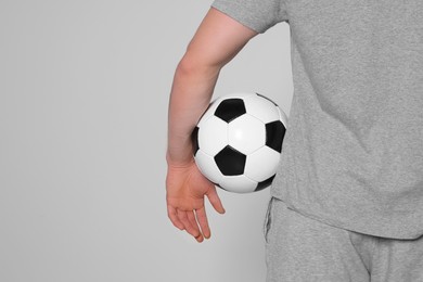 Photo of Athletic man with soccer ball on light grey background, closeup. Space for text
