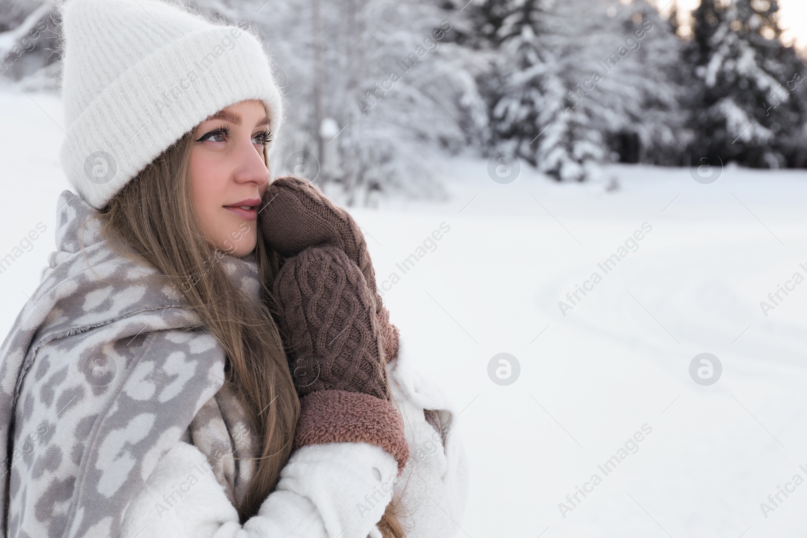 Photo of Winter vacation. Beautiful woman near snowy forest outdoors. Space for text