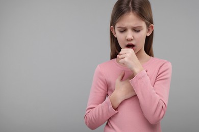 Photo of Sick girl coughing on gray background, space for text