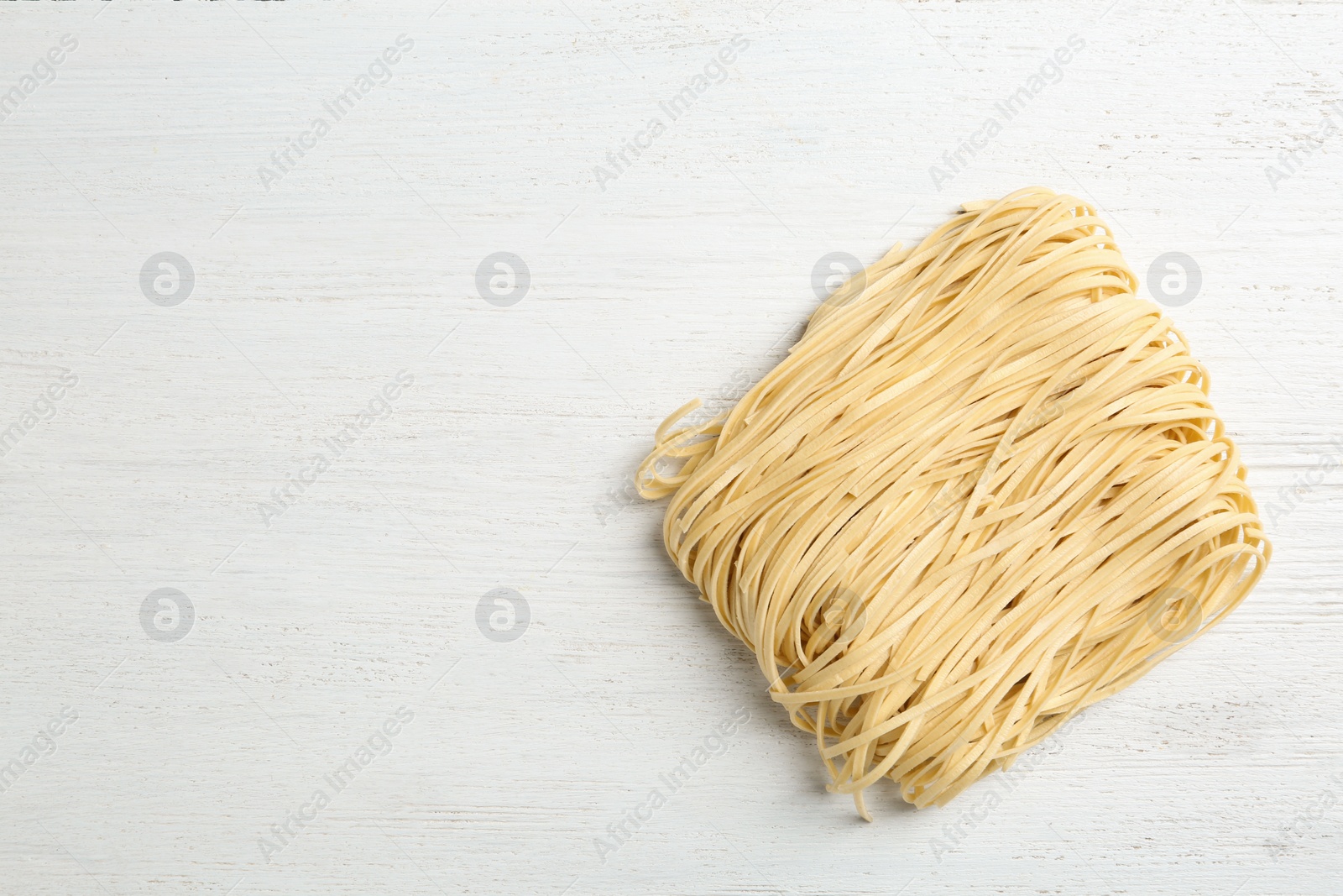 Photo of Block of quick cooking noodles on light wooden background, top view. Space for text