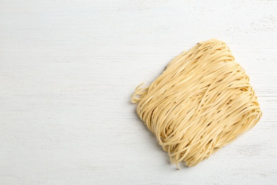 Block of quick cooking noodles on light wooden background, top view. Space for text