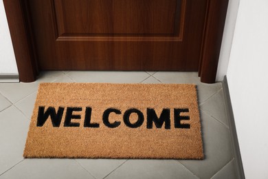 Door mat with word Welcome on floor near entrance, above view