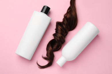 Photo of Lock of hair and shampoo bottles on pink background, flat lay