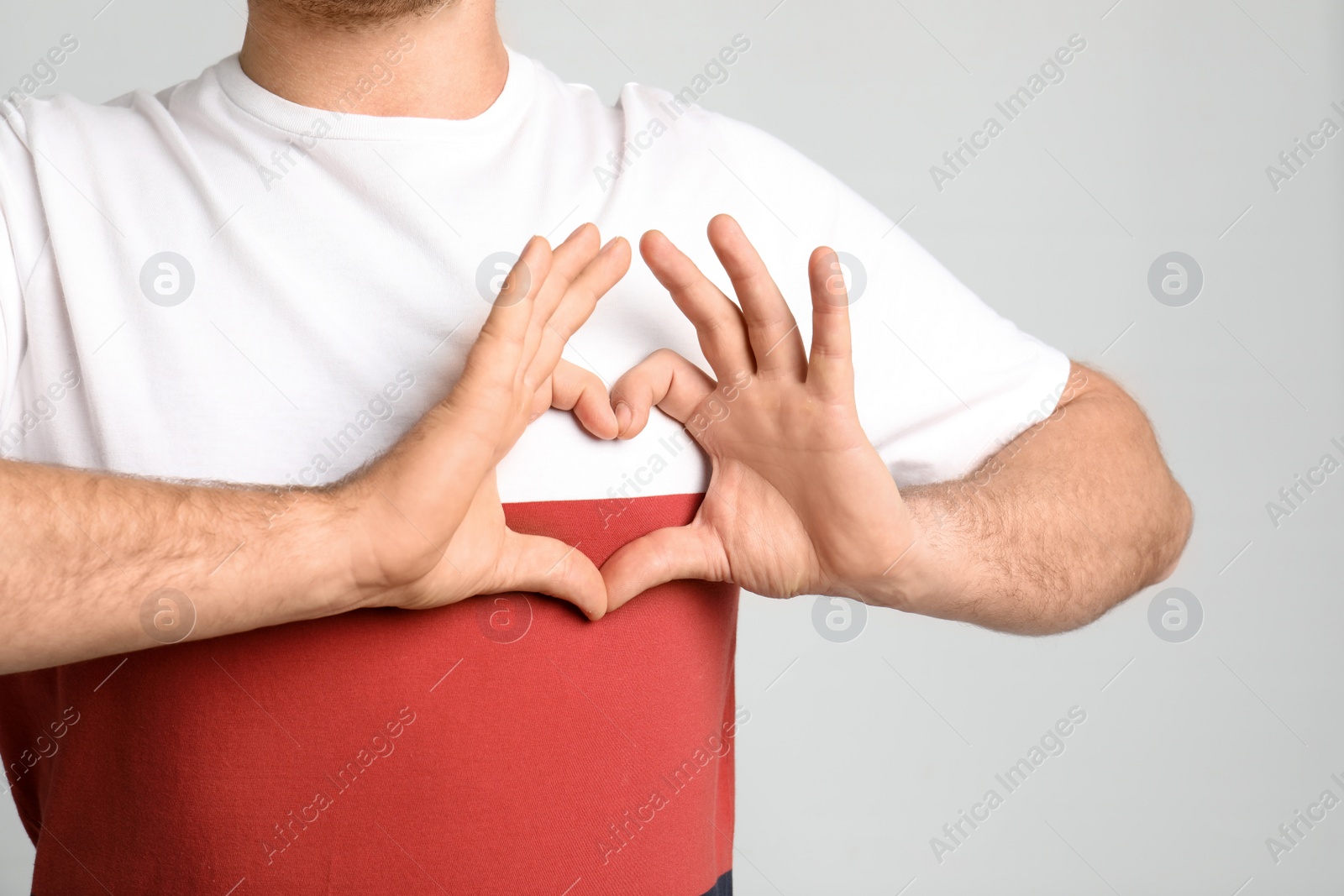 Photo of Man making heart with his hands on light background, closeup