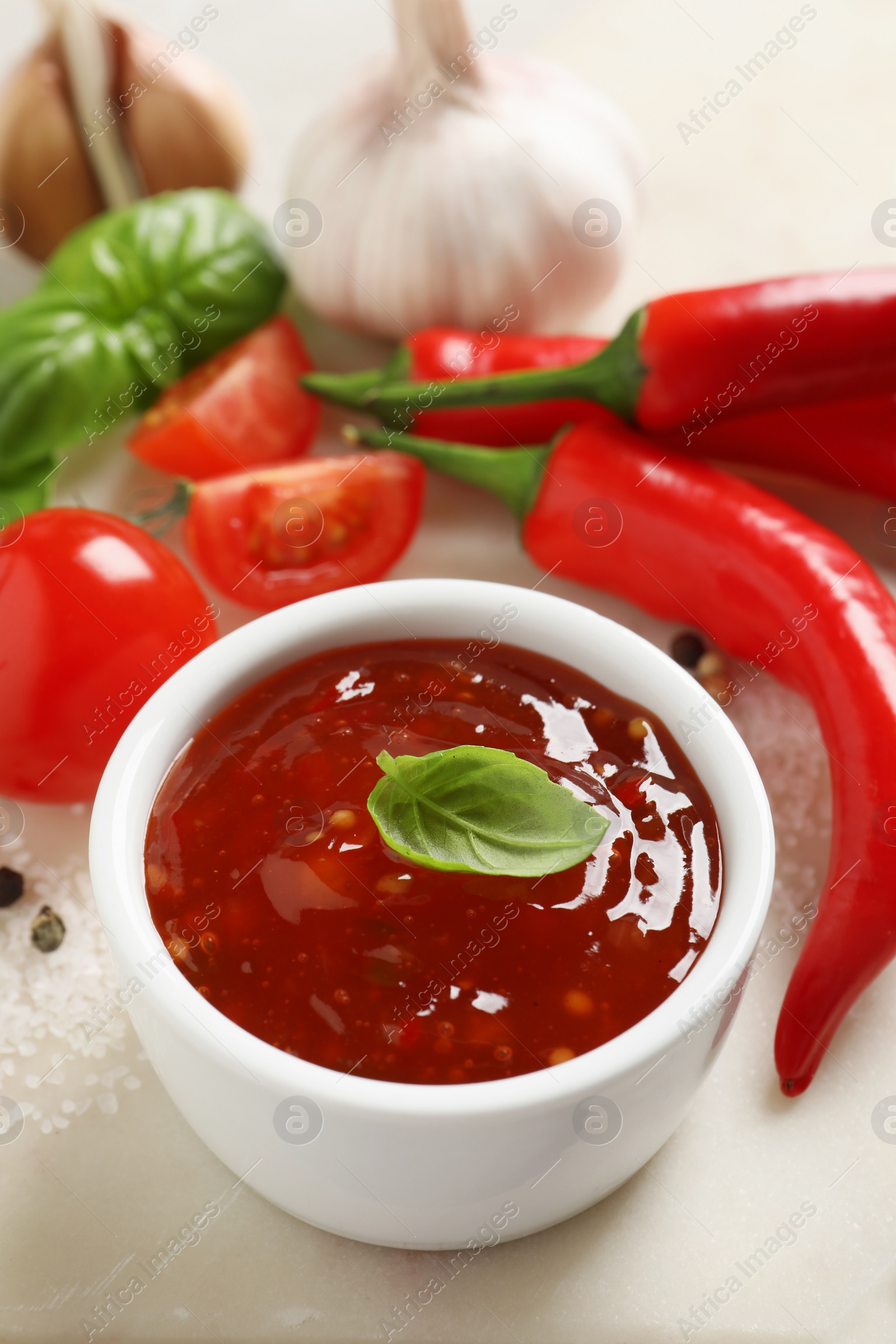 Photo of Spicy chili sauce with basil on table