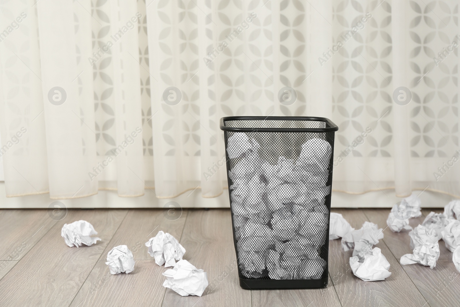 Photo of Basket with crumpled paper on floor indoors. Space for text