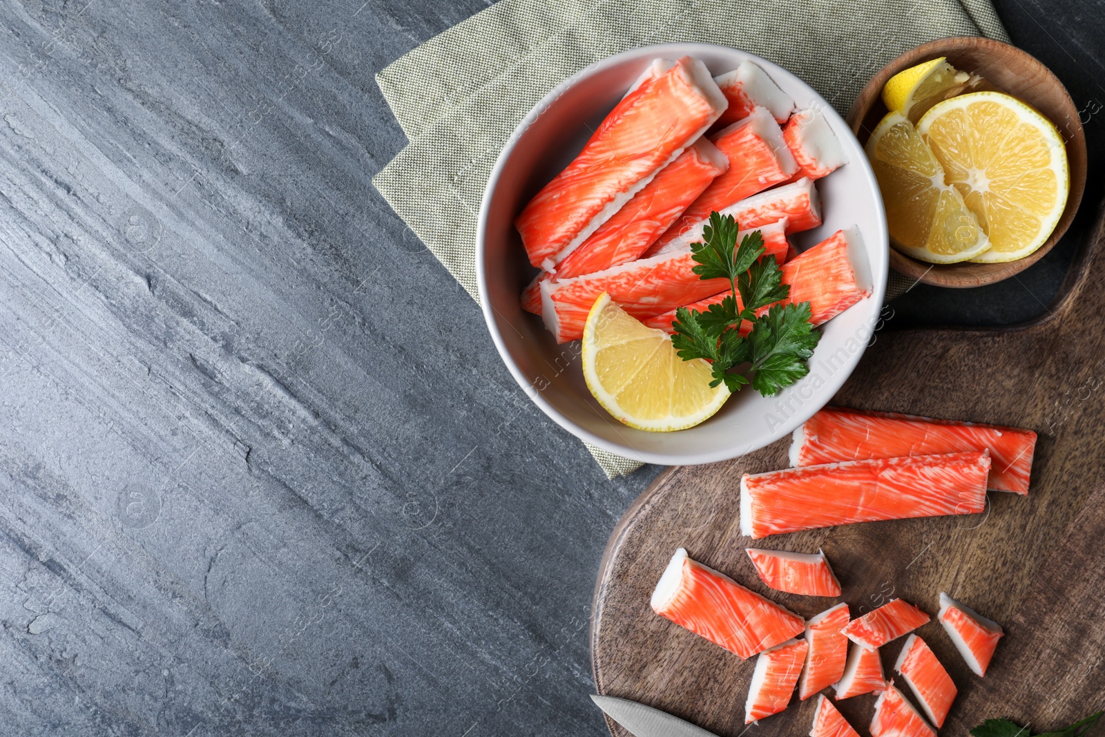 Photo of Flat lay composition with crab sticks and lemon on grey background, space for text