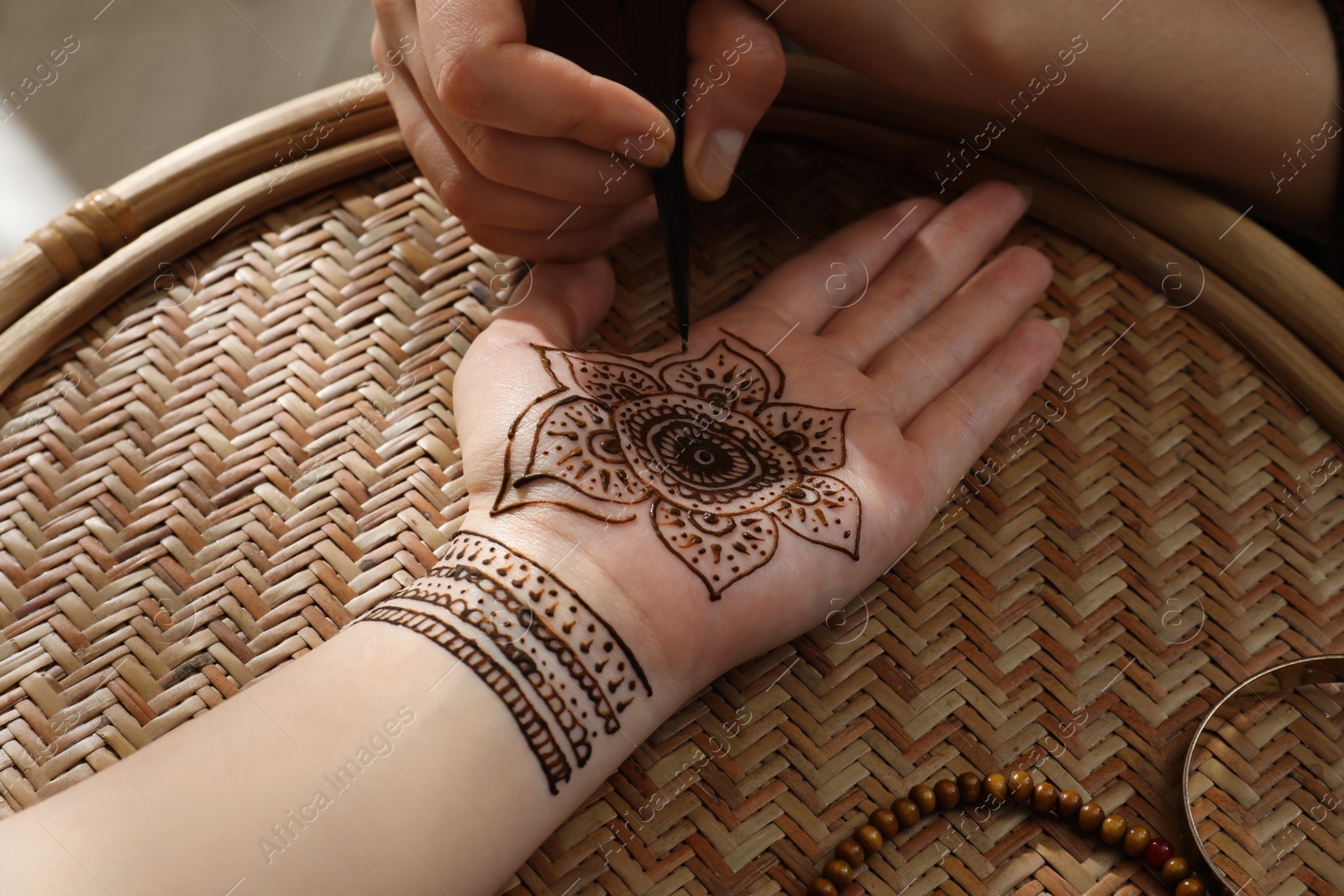 Photo of Master making henna tattoo on hand, closeup. Traditional mehndi