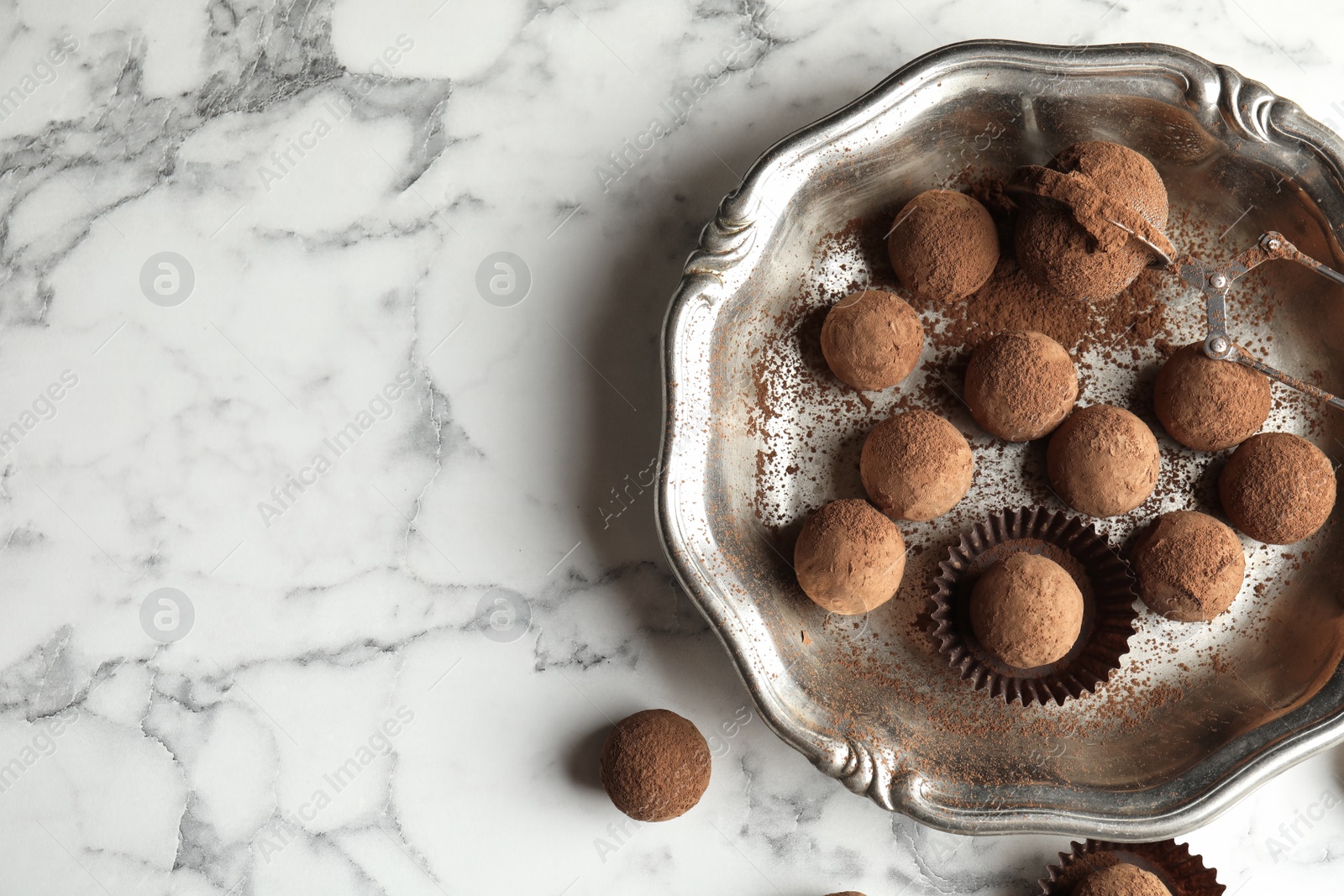 Photo of Plate of tasty chocolate truffles on marble background, top view with space for text