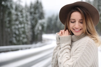 Photo of Young woman in warm sweater outdoors, space for text. Winter vacation