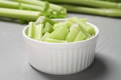 Photo of Bowl with fresh green cut celery on light grey table, closeup