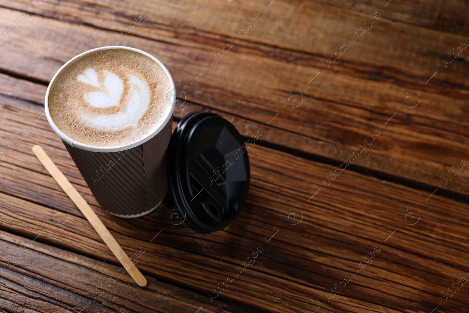 Photo of Coffee to go. Paper cup with tasty drink on wooden table, space for text