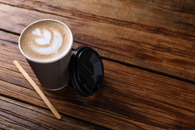 Coffee to go. Paper cup with tasty drink on wooden table, space for text