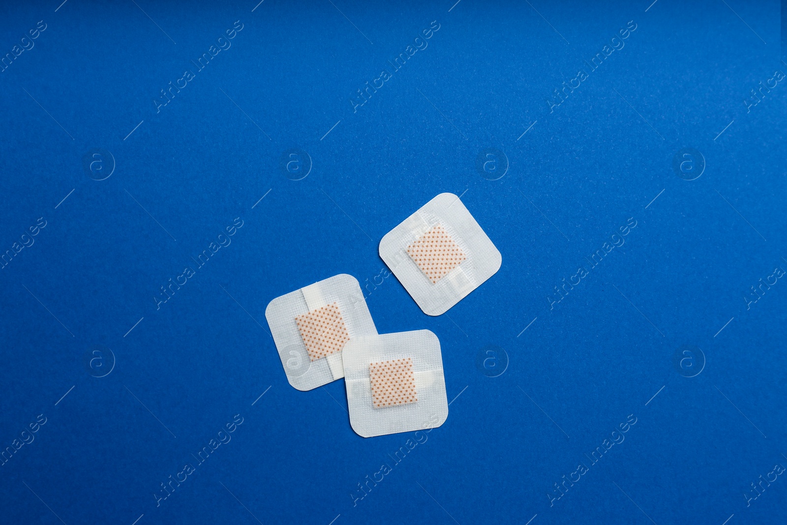 Photo of Sticking plasters on blue background, flat lay