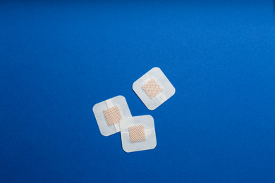Photo of Sticking plasters on blue background, flat lay