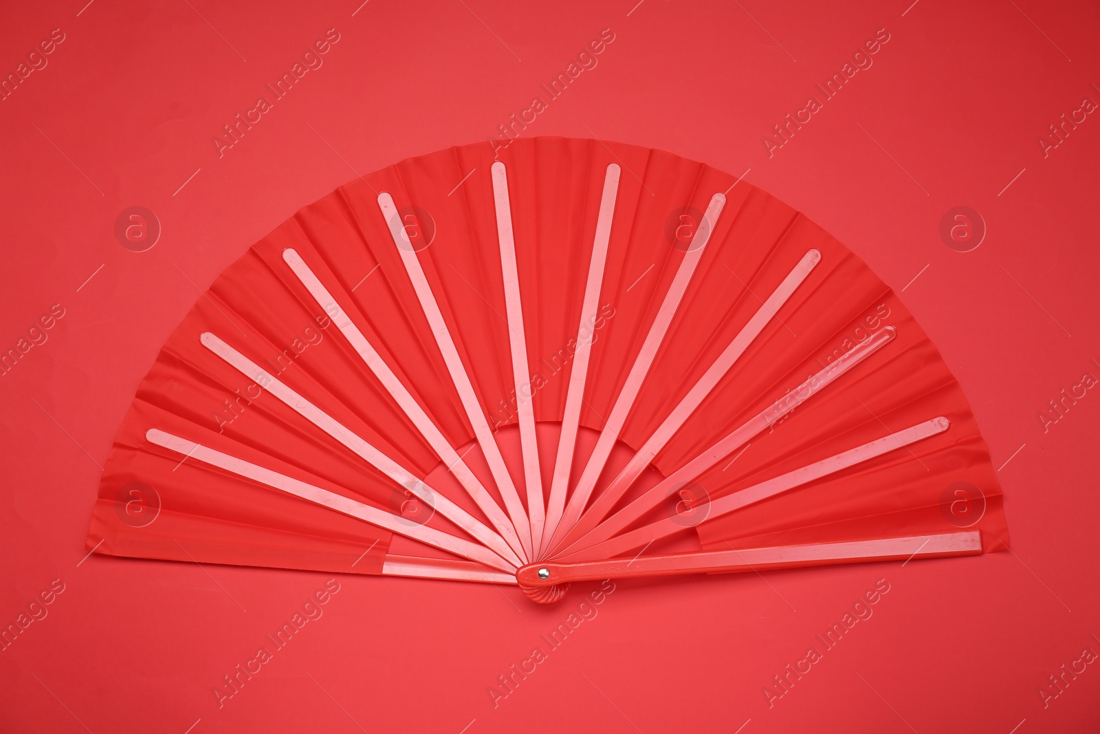 Photo of Bright color hand fan on red background, top view