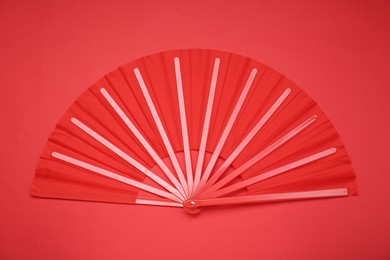 Photo of Bright color hand fan on red background, top view