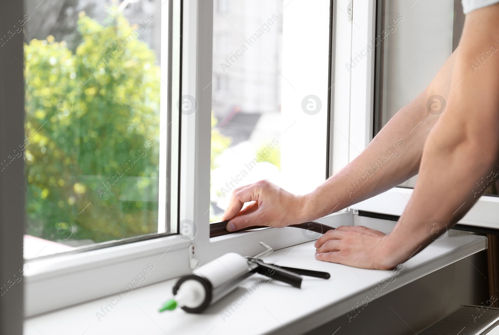 Photo of Construction worker putting sealing foam tape on window indoors