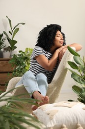 Photo of Woman relaxing in armchair surrounded by beautiful houseplants at home