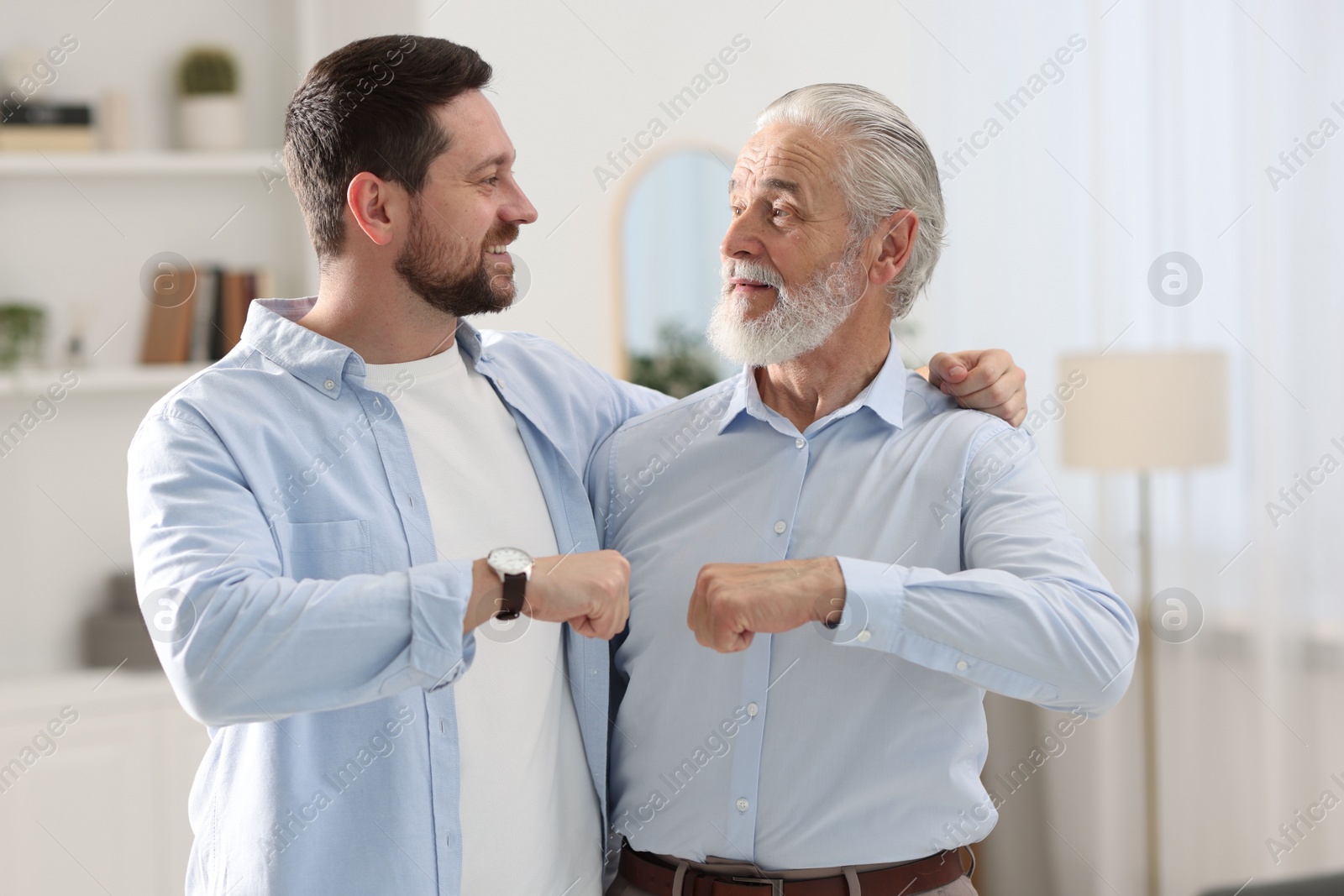 Photo of Happy son and his dad making fist bump at home