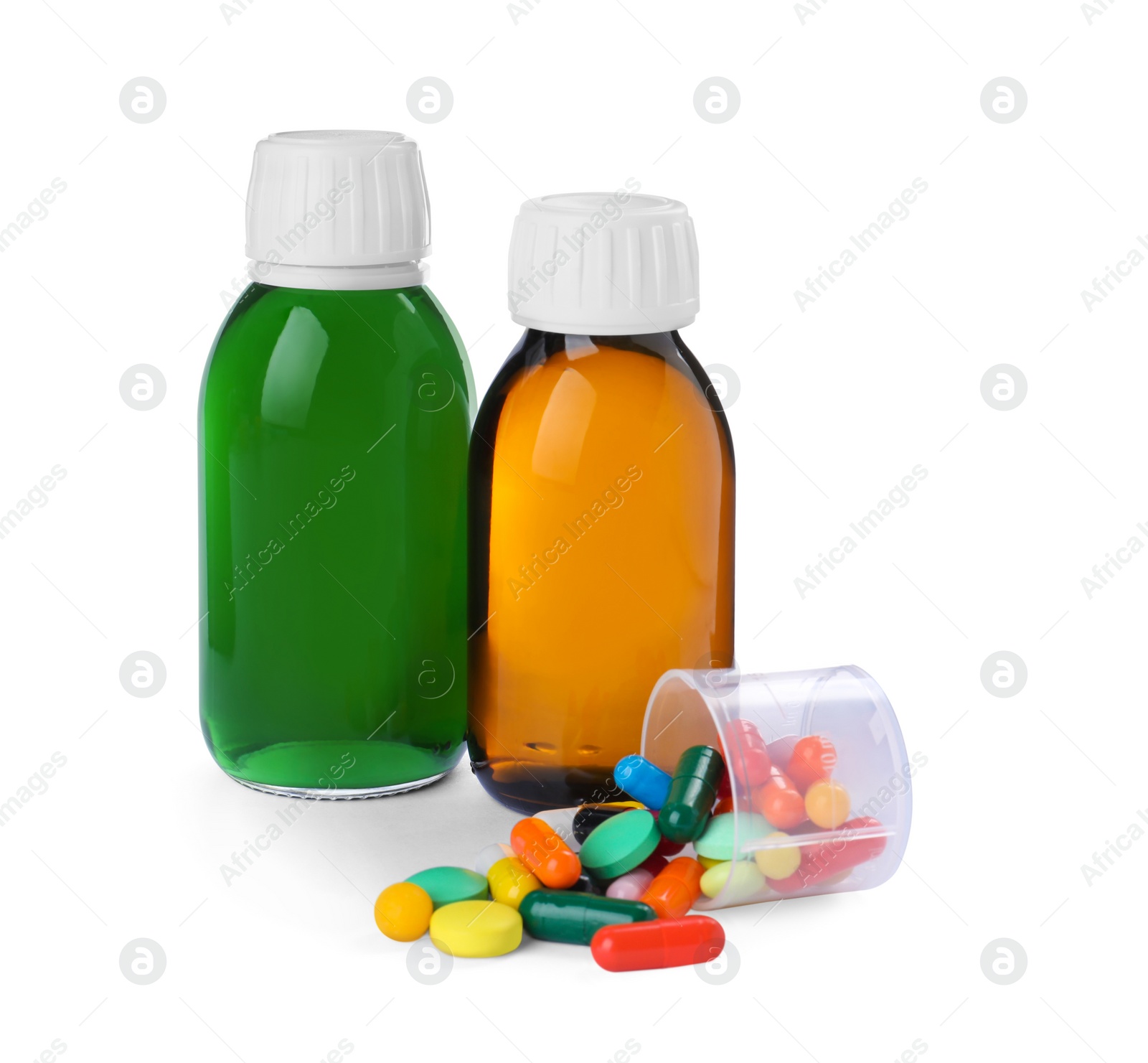 Photo of Bottles of syrups, measuring cup with pills on white background. Cough and cold medicine