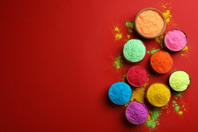 Colorful powders in bowls on red background, flat lay with space for text. Holi festival celebration