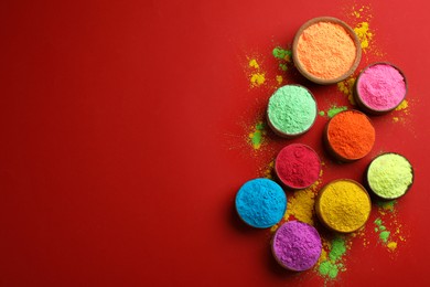 Photo of Colorful powders in bowls on red background, flat lay with space for text. Holi festival celebration