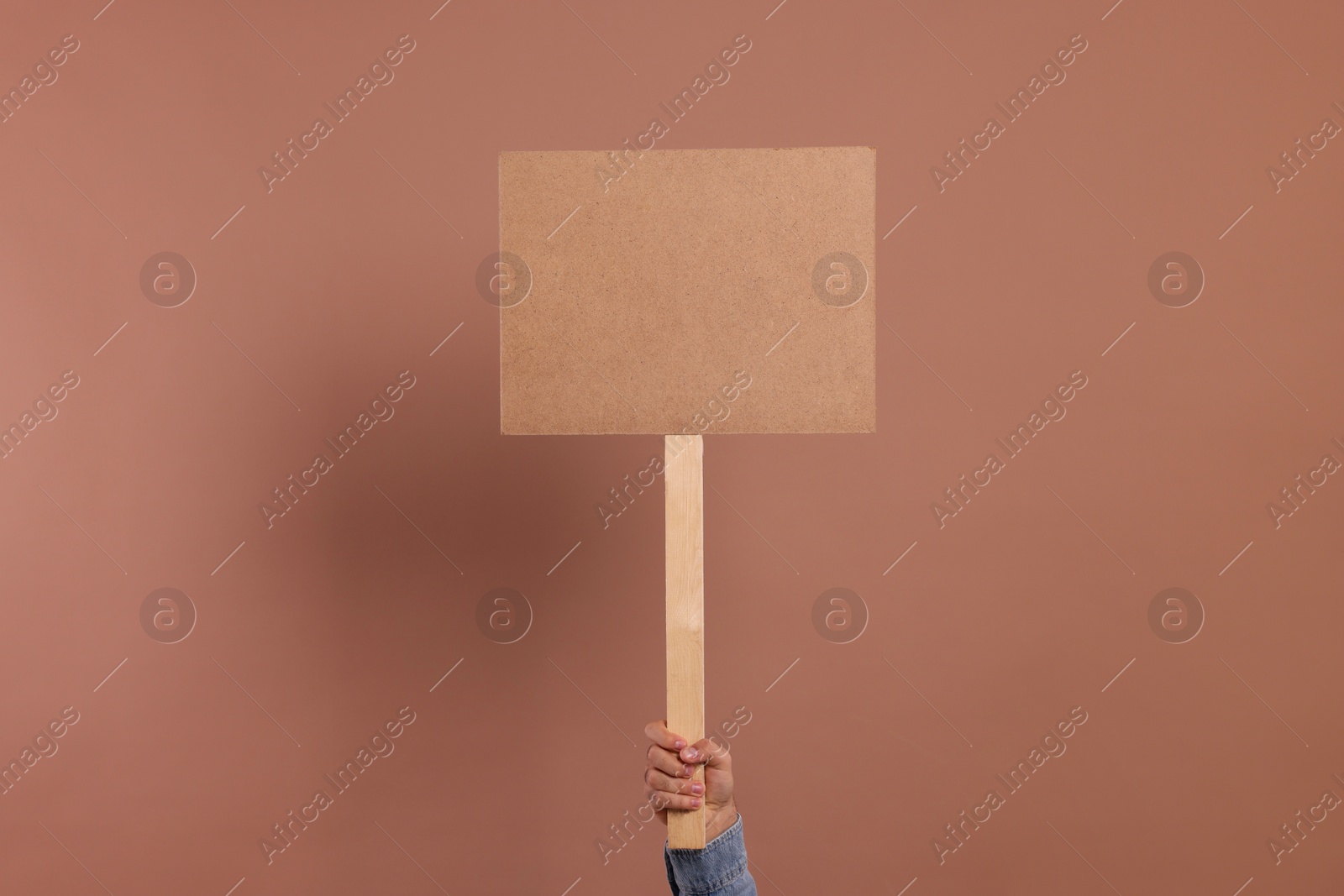 Photo of Man holding blank sign on brown background, closeup. Space for text