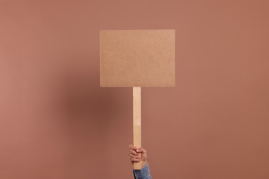 Photo of Man holding blank sign on brown background, closeup. Space for text