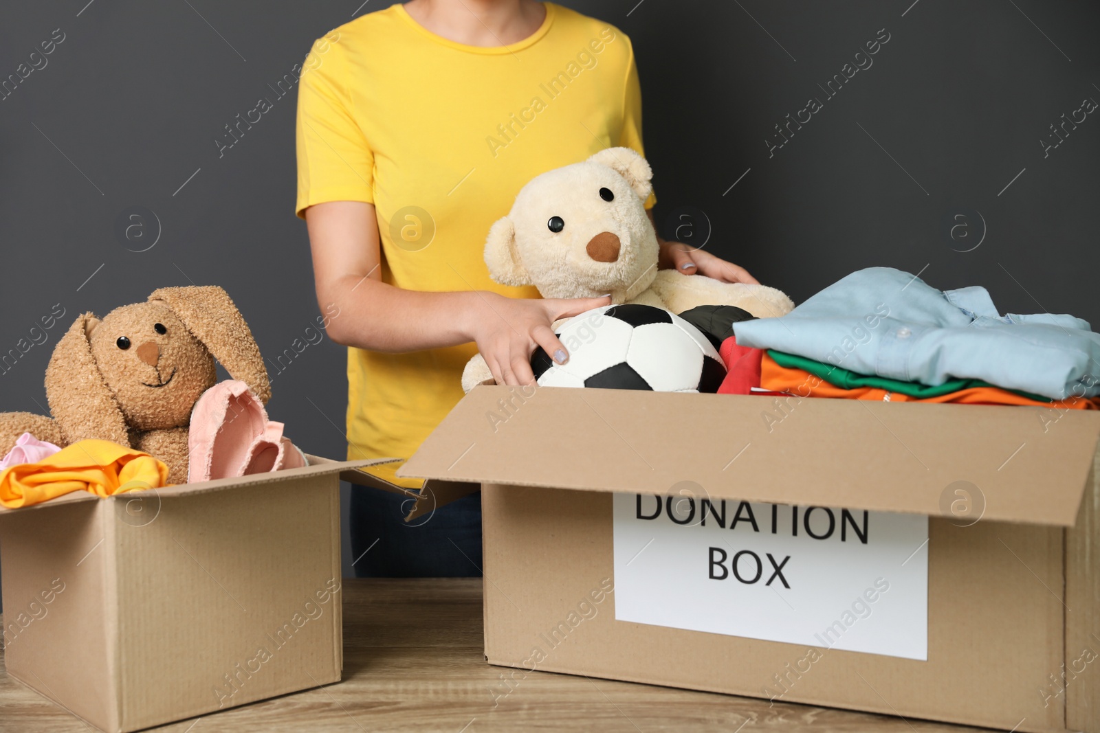 Photo of Young woman collecting donations at table on grey background