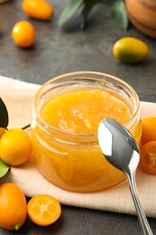 Photo of Delicious kumquat jam and fresh fruits on table
