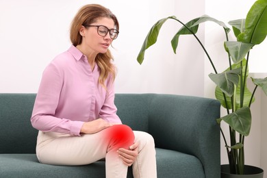 Woman suffering from rheumatism in knee at home