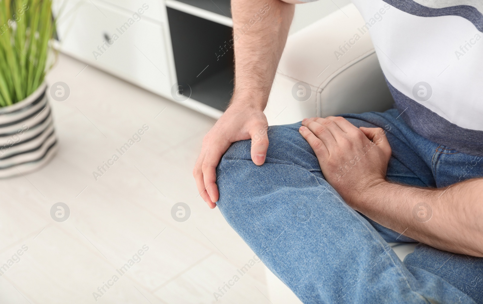 Photo of Young man suffering from leg pain indoors, closeup. Space for text