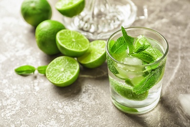 Photo of Refreshing beverage with mint and lime in glass on table