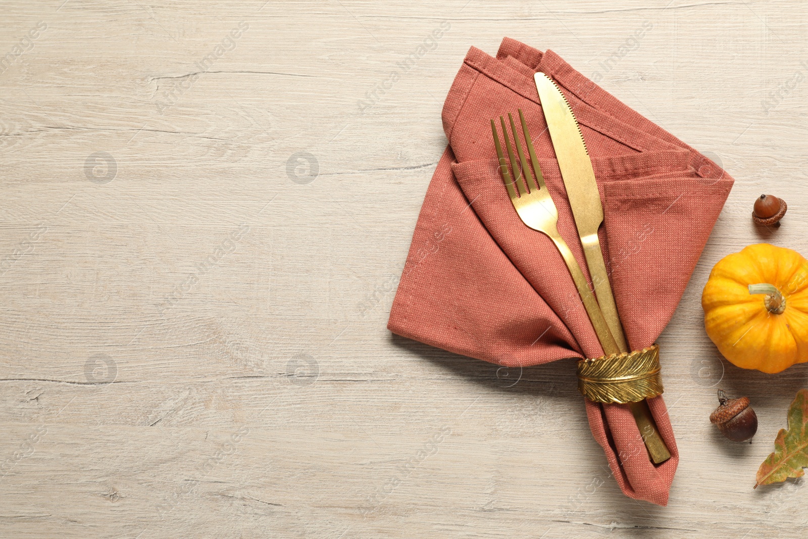 Photo of Cutlery, napkin and pumpkin on wooden background, flat lay with space for text. Table setting